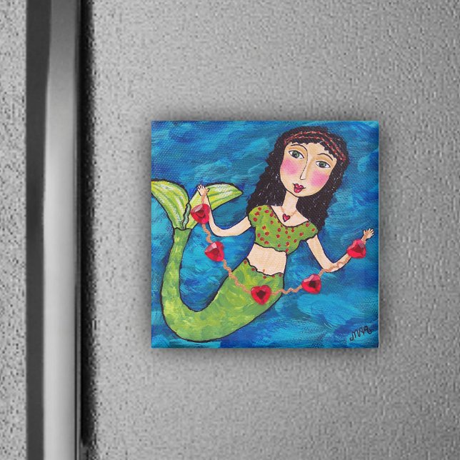 Sirena Con Imán Cardíaco (Mermaid green tail holding gold string of red heats on ocean blue magnet.)
