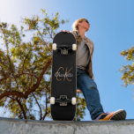 Skateboard Minimalista elegante del guión de oro negro<br><div class="desc">Un fondo negro clásico. Personalice y agregue un nombre y iniciales de monograma. El nombre está escrito con una escritura de estilo con letras a mano moderna. Letras blancas y doradas.</div>