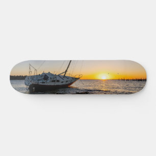 Skateboard Puesta de sol en tabla de surf en el muelle y vele