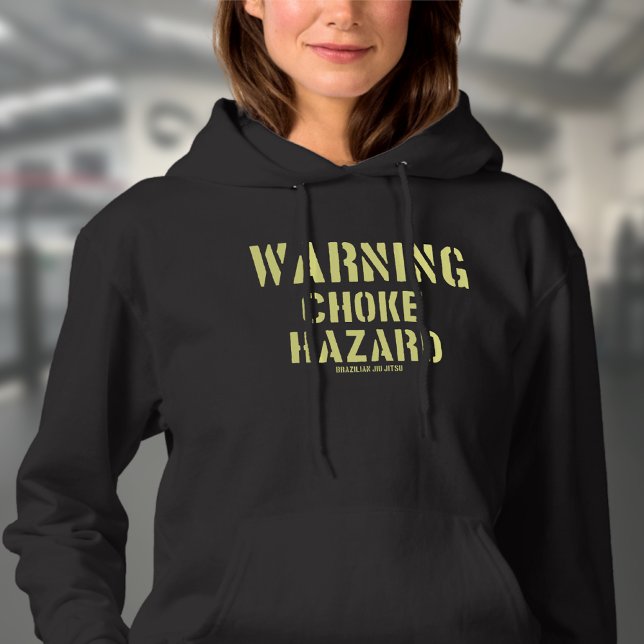 Sudadera Choque de advertencia de BJJ Hazard brasileño Jiu  (Choke hazard woman's black hoodie worn by a female model in a gym.)