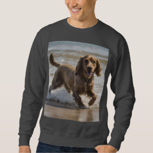 Sudadera "Diversión costera: Cocker Spaniel juega en el océ