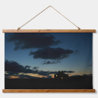 Tapiz Con Marco De Madera Una casa solitaria en el horizonte al atardecer.