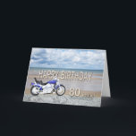 Tarjeta 80th birthday card with a motor bike<br><div class="desc">A blue motor cycle standing on a beach with fluffy clouds in the sky. Happy Birthday written in rock reflected in the water lying on the sand.</div>