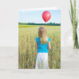 Tarjeta chica en campo de trigo con globo rojo