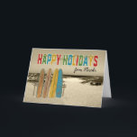 Tarjeta Christmas Card with Vintage Surfboards on Beach<br><div class="desc">A nostalgic graphic creation for this vintage looking Merry Christmas card featuring vintage looking long boards standing up against a rustic wooden stand in the sand with the ocean in the distance. Bold letters spell out Happy Holidays and holiday lights are draped over them. Great card for a surfer and...</div>