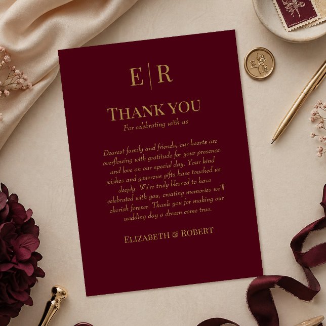 Tarjeta de agradecimiento de boda con monograma de (Elegant Burgundy Monogram Wedding Thank You Card on a table with burgundy wedding decor)