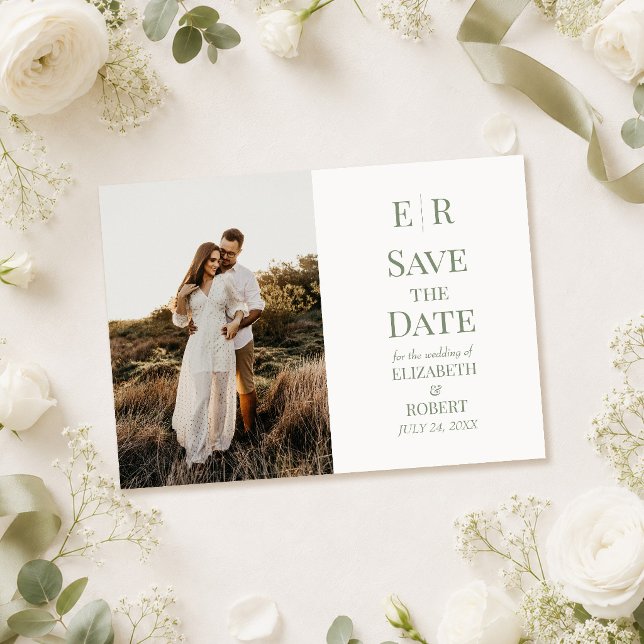 Tarjeta de anuncio de fecha de boda con monograma  (White & Olive Monogram Photo Save the Date Card on a  table with white flowers)