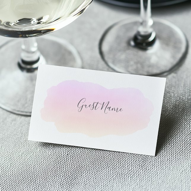 Tarjeta de bienvenida color agua rosa suave (Soft watercolor pink paint wash on a white guest name place card at a wedding dining table)