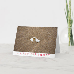 Tarjeta de cumpleaños con concha rota en una playa