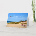 Tarjeta de felicitación de Beach Santa<br><div class="desc">Un caprichoso Navidad saludando a Santa y a su hijo en la playa con un avión que cuelga en el cielo y que volaba un mensaje de Feliz Navidad.</div>