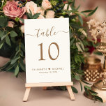 Tarjeta De Mesa Recepción de la boda crema con guión dorado de la<br><div class="desc">Moda crema marca de la recepción numero de la mesa de la recepción de la boda con "mesa" en un elegante guión de caligrafía dorada con toques, el número de la mesa en la tipografía clásica de la sierra dorada, sus nombres unidos por un corazón y la fecha de recepción....</div>