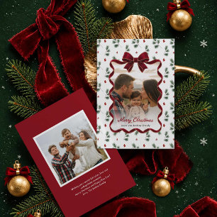 Tarjeta de Navidad con lazo rojo y vegetación inve