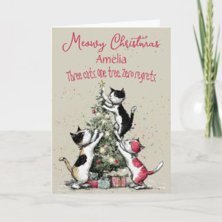 Tarjeta de Navidad de tres gatos decorando un árbo