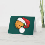 Tarjeta de Navidades del baloncesto Santa Cap<br><div class="desc">Baloncesto con una gorra de santa con un resorte de holly para Navidades. El fondo es verde,  pero el color de fondo se puede cambiar haciendo clic en "Personalizar". Dentro de la tarjeta están las palabras "Felices Fiestas" que también se pueden personalizar.</div>