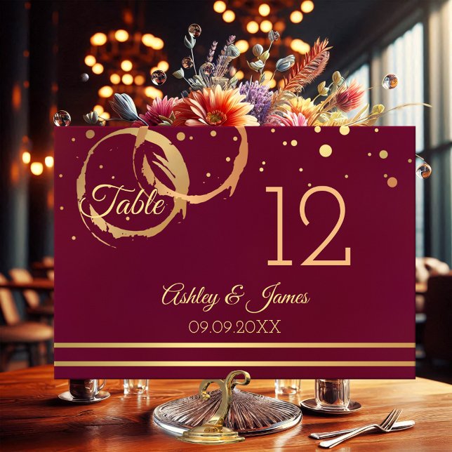 Tarjeta de número de mesa del Rosa Gold Marsala Wi (Table number card featuring rose gold and gold wine stain rings with sparkling confetti on burgundy)