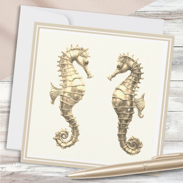 Tarjeta Dos caballitos de mar de oro elegantemente para la (A note card with two golden seahorses on an elegant cream background)