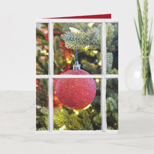 Tarjeta Festiva adorno navideño rojo en ventana nevada