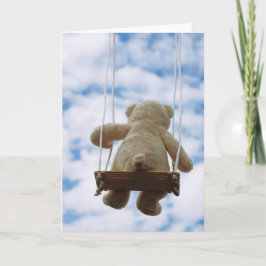Tarjeta Festiva Beertje op schommel met bewolkte blauwe lucht.