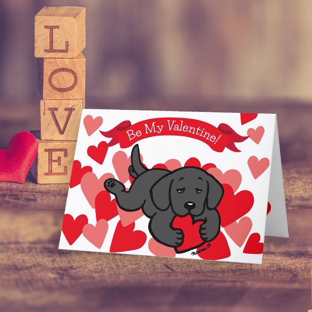 Tarjeta Festiva Black Labrador Puppy masticando el corazón Valenti (Black Labrador Puppy Chewing Heart Valentine's Day Cards for Labrador Owners.  Cute Cartoon design.)
