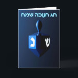 Tarjeta Festiva Dreidel azul brillante<br><div class="desc">Un dreidel modernista,  metálico y azul sobre un fondo oscuro y nocturno. Dos de las letras hebreas encontradas en un dreidel,  una monja y un shin,  brillan brillantemente. El texto en hebreo que dice "Chag Chanukkah Sameach" (Feliz Hanukkah) también aparece en azul y blanco resplandeciente.</div>