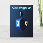 Tarjeta Festiva Dreidel azul brillante<br><div class="desc">Un dreidel modernista,  metálico y azul sobre un fondo oscuro y nocturno. Dos de las letras hebreas encontradas en un dreidel,  una monja y un shin,  brillan brillantemente. El texto en hebreo que dice "Chag Chanukkah Sameach" (Feliz Hanukkah) también aparece en azul y blanco resplandeciente.</div>