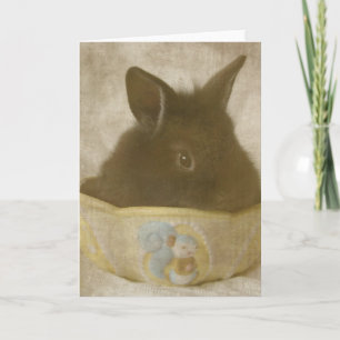 Tarjeta Festiva El conejito de Pascua en un plato de golosinas