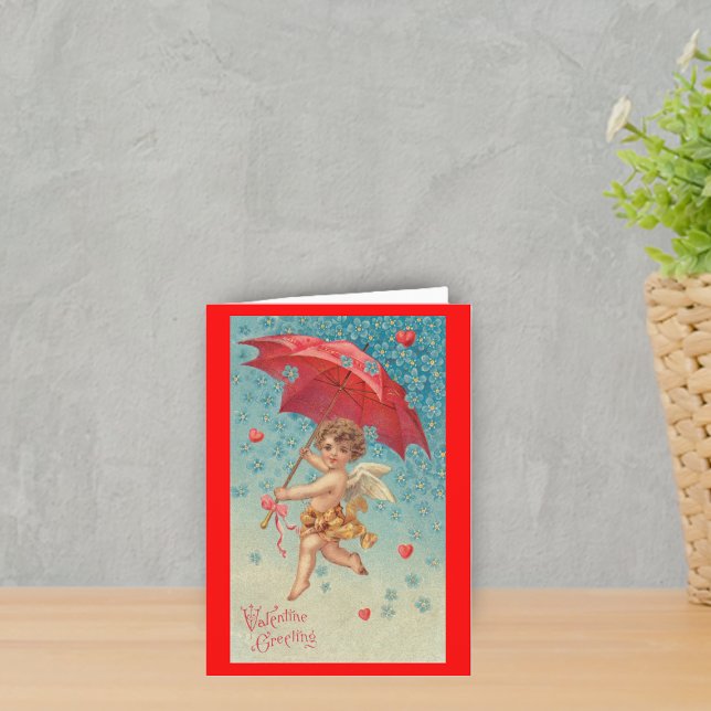 Tarjeta Festiva El paraguas de San Valentín Cupido (Victorian flying cupid red umbrella harts snowflakes on red Valentine's greeting card.)