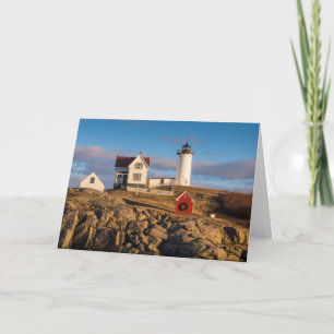 Tarjeta Festiva Faro al atardecer con decoraciones navideñas