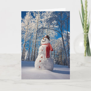 Tarjeta Festiva Hombre de nieve frente a bosque cubierto de nieve