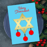 Tarjeta Festiva Merry Chrismukkah Star of David and Ornaments<br><div class="desc">Esta tarjeta Merry Chrismukkah presenta una estrella dorada de David en el centro sobre un fondo azul. Hay tres ornamentos rojos de Navidad colgados de la Estrella de David. La parte superior de la tarjeta incluye las palabras "Merry Chrismukkah" en rojo. En la parte trasera de la tarjeta plana está...</div>