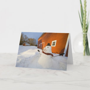 Tarjeta Festiva Muñeco de nieve delante del granero rojo en las
