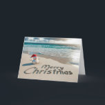 Tarjeta Festiva Navidades tropicales Snowman en una playa<br><div class="desc">Un pequeño muñeco de nieve de arena con un sombrero de Santa se para en una playa de arena con "Feliz Navidad" escrito en la arena</div>