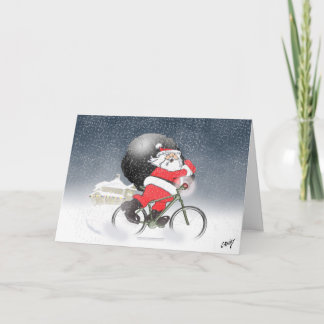 Tarjeta Festiva Santa en bicicleta con su saco en la nieve.
