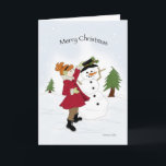 Tarjeta Festiva Snowman y la pequeña niña<br><div class="desc">Niña pequeña con un abrigo rojo vistiendo a un muñeco de nieve en la nieve</div>