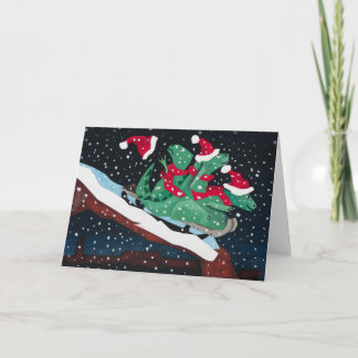 Tarjeta Festiva Three sledding dinosaurs