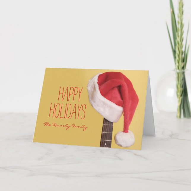 Tarjeta Festiva Un gorra de Santa cuelga en una guitarra acústica (Anverso)
