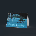 Tarjeta Festiva Winter Wolf - Saludos de temporada<br><div class="desc">Un lobo camina sobre una nieve dura en la noche; un pico cubierto de árboles en el fondo. La luz de la luna refleja la nieve y la ladera pálida de los abedules. Los ojos del lobo también brillan con la luz de la luna reflejada. El texto que dice "Saludos...</div>
