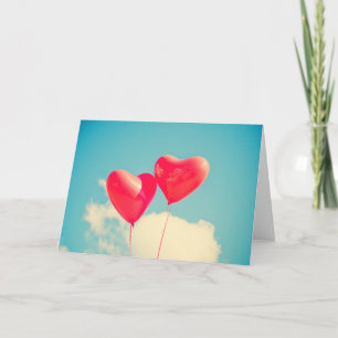 Tarjeta Globos del corazón rojo contra cielo nublado