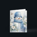 Tarjeta Gorra de Snowman y árboles cubiertos de nieve en b<br><div class="desc">Hombre de nieve adorable con gorra azul y bufanda sosteniendo flores blancas de bonito en este frío día de invierno.</div>