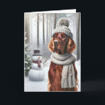 Tarjeta Navidades irlandeses sentados con hombre de nieve<br><div class="desc">Un perro con un gorra de punto gris y una bufanda parados en un bosque de nieve al lado de un muñeco de nieve para Navidades</div>