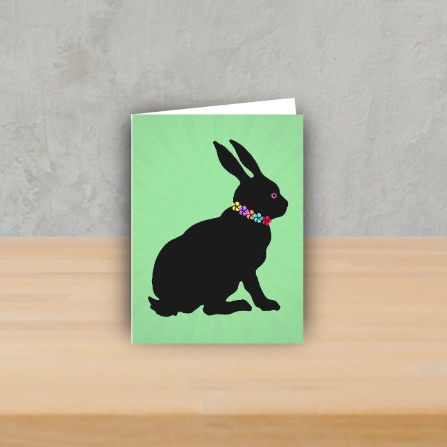 Tarjeta Perfil lateral sentada Flores de conejo negro Ojo  (Sitting black silhouette bunny wearing colourful flowers on green Spring or Easter note card.)