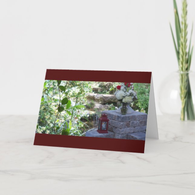 Tarjeta Una pared de piedra en un jardín verde sobre un (Anverso)