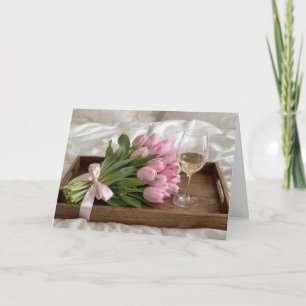 Tarjeta Vino de cumpleaños y tulipanes rosados en sábanas 