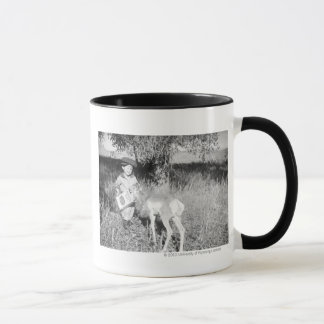 Taza Antílope de alimentación del muchacho a mano