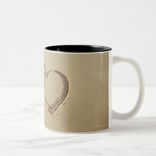 Taza Bicolor Dos corazones sobrepuestos dibujados en la playa