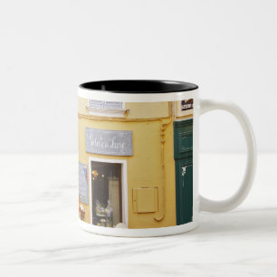 Taza Bicolor Una calle comercial en el casco antiguo con una ti