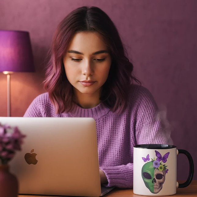 Taza blanca con diseño calavera alien y mariposa – (Una joven mirando sus cosas en el ordenador mientras se toma una bebida caliente en su taza favorita)