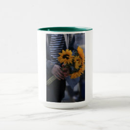 Taza blanca donde una mano sostiene girasoles con 