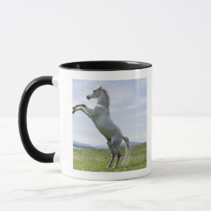 Taza caballo blanco que salta en prado