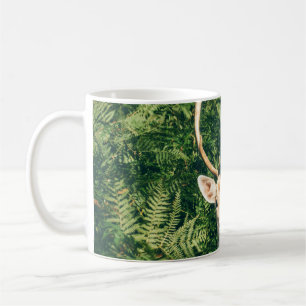 TAZA DE CAFÉ CERVEZA BLANCA Y MARRÓN RODEADA DE PLANTAS VERDES